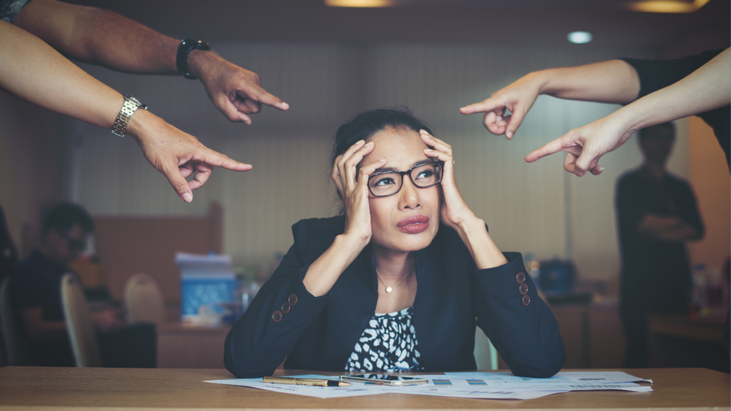 cultura del miedo en las empresas — empleada bajo presión y señalada por compañeros en el trabajo