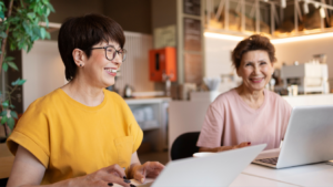 Dos profesionales de diferentes generaciones colaborando con un portátil, ejemplo de diversidad generacional en el trabajo